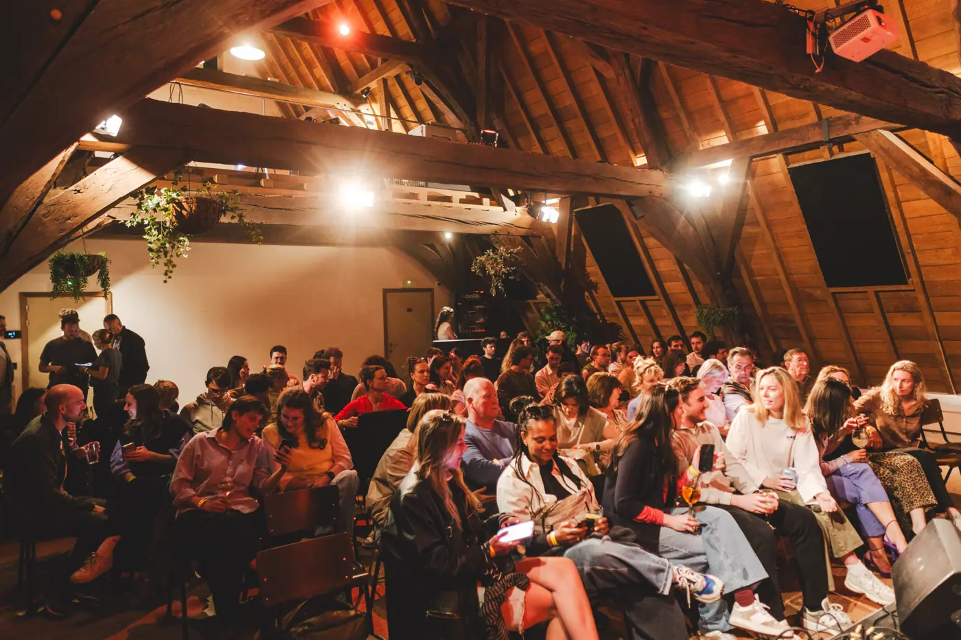 Zittend publiek onder houten spanten tijdens editie 2