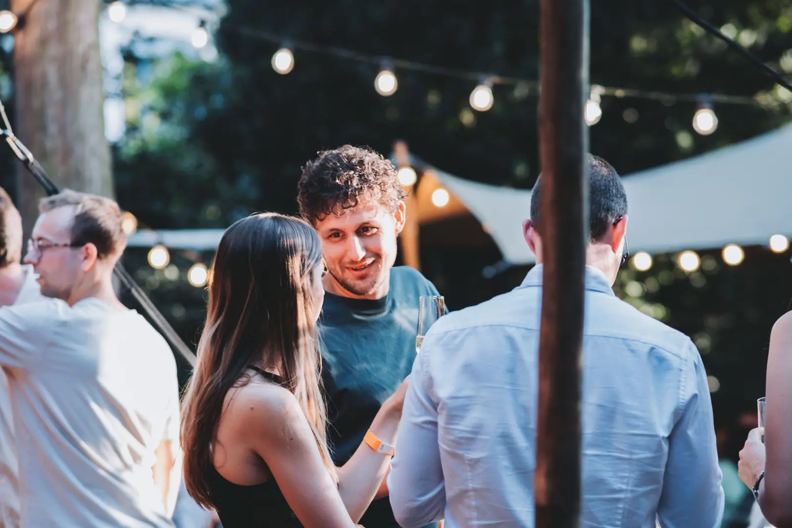 Bezoekers in gesprek onder lichtslingers in de tuin